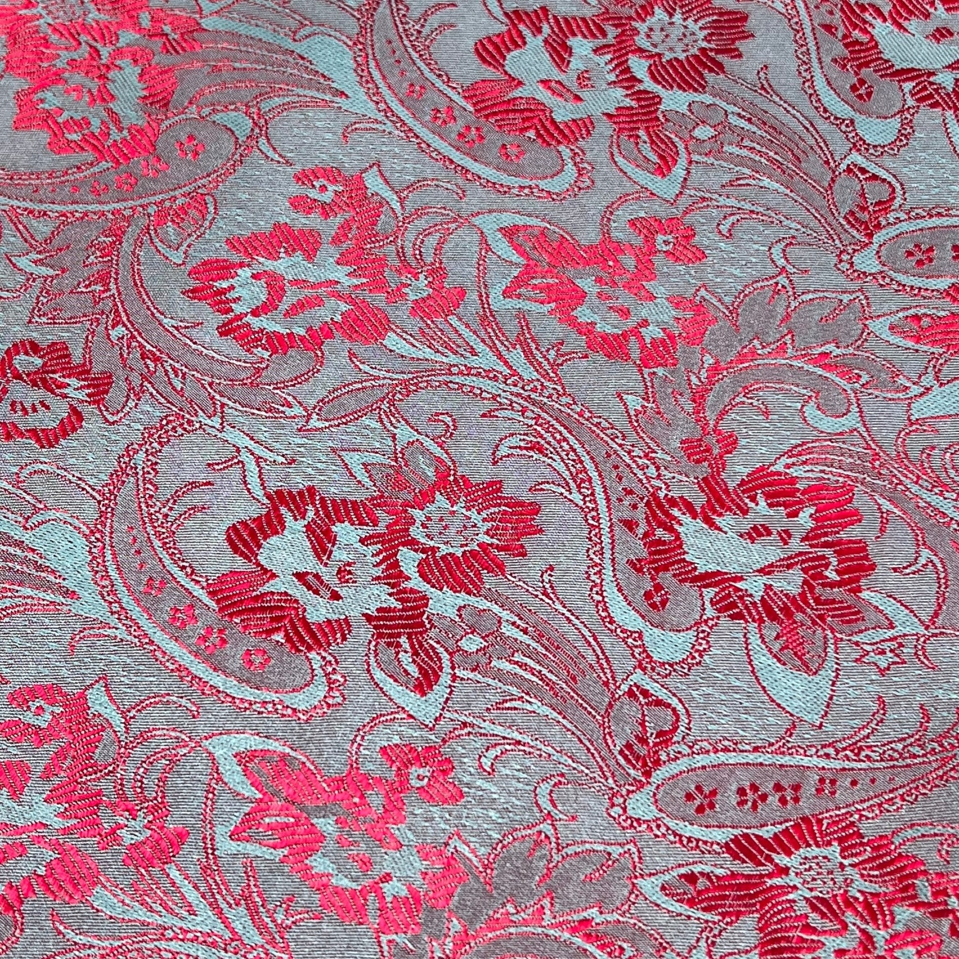 Close-up of a vibrant floral pattern in red and blue on a silver background, showcasing delicate Thai silk craftsmanship.